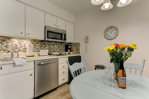 The unit is equipped with a full kitchen, excluding an oven, and features a dining table.
