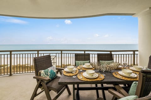 Oceanfront balcony with dining table and sweeping beach views