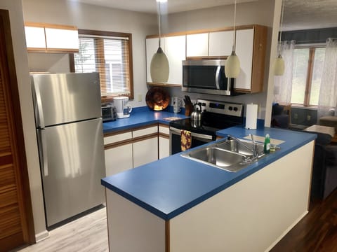 Fully equipped kitchen with pots and pans, plates, cups, coffee maker, glasses