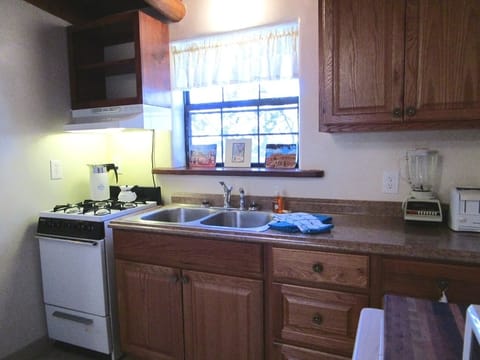 Small kitchen with apartment sized 4-burner gas stove/oven and double sink. 
