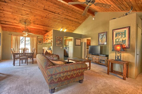 A cozy living space with a high, wooden ceiling, a plush coach and a TV set up. 