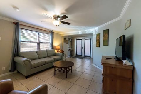Comfortable living room with double door entry, smart tv and ceiling
 fan. 