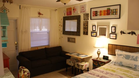 Queen size bed,sofa, wall mounted drop-leaf table and stools for dining.