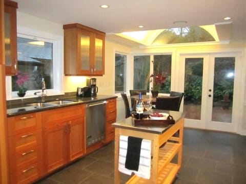 Deluxe gourmet kitchen with marble pub table and french doors open to large deck