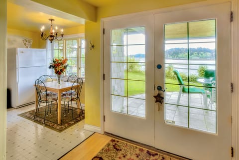Entry door with patio seating outside & kitchen table and full fridge on left