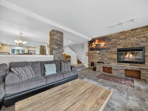 Unwind on the plush sectional sofa while the stone fireplace radiates warmth and character throughout your open living space.