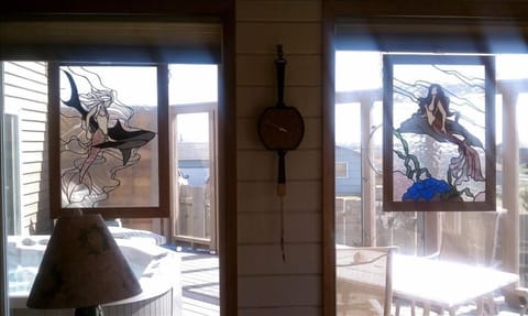 Two beautiful stained glass mermaid panels in the living room windows.