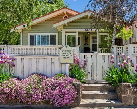 A picturesque entrance with blooming flowers, birch trees and a copper roof