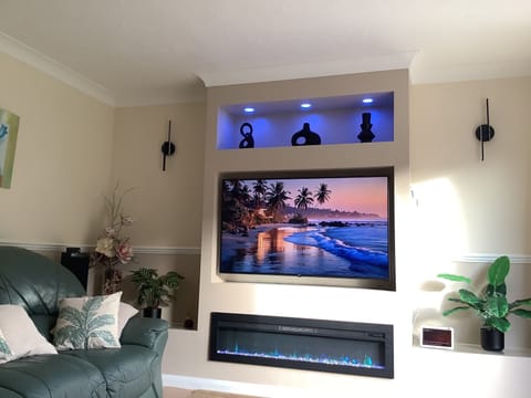 The bright lounge area features a wall-mounted 55” Smart TV set in a media wall