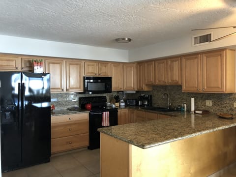 Large kitchen with granite countertops, stocked with coffeepot, blender & more