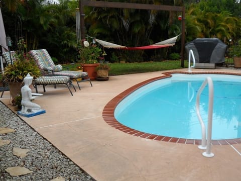 Many seating areas around the blue glistening pool, including gas grill.