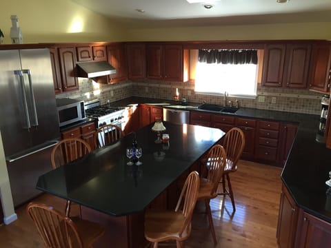 Chef's kitchen with sliding doors to patio and window overlooking the playground