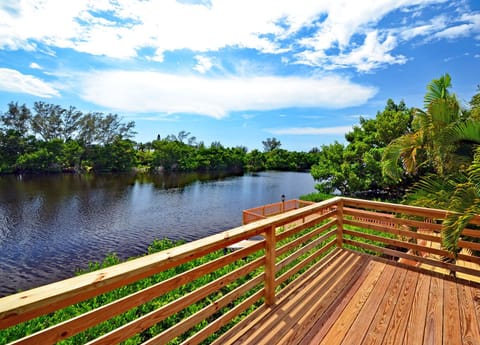Wooden balcony with railing overlooking calm lake water lined with green vegetation