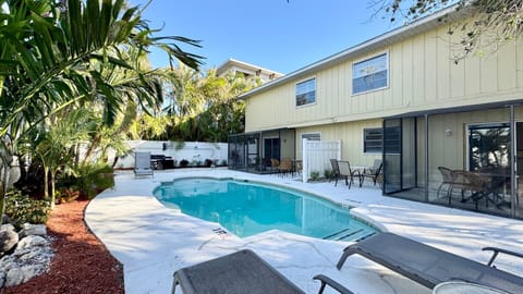 Private pool with lounge chairs and patio seating surrounded by tropical landscaping