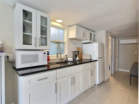 A compact kitchenette with cabinets, countertop, sink, and appliances.