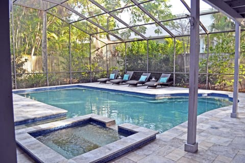 Screened pool enclosure with pool, spa, and lounge chairs on the deck