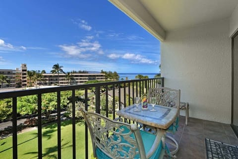 Balcony dining set for two with garden, ocean, and distant mountain views.