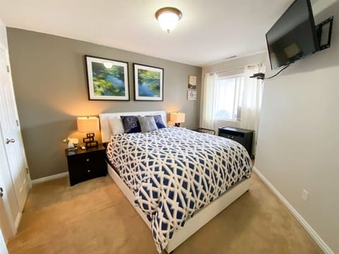 Cozy bedroom with plush bedding, soft lighting, and wall-mounted TV