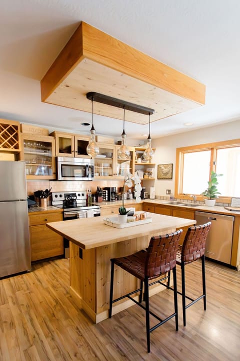 The kitchen, a blend of farmhouse charm and mountain chic, is fully stocked and features a butcher block island, stainless appliances, and a welcoming ambiance perfect for cooking and socializing.
