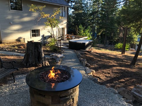 Fire table seating area overlooking deck and spa with lake, mountain view.