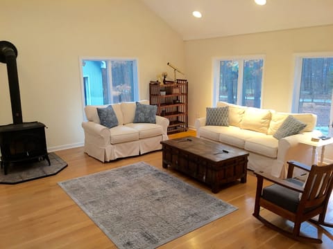Living room with 65' TV, wood burning fireplace, and 15' ceiling with skylights