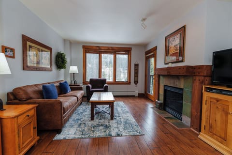 Relax in your cozy living room featuring warm leather seating, a rustic stone fireplace, and natural wood accents that create the perfect mountain retreat atmosphere.