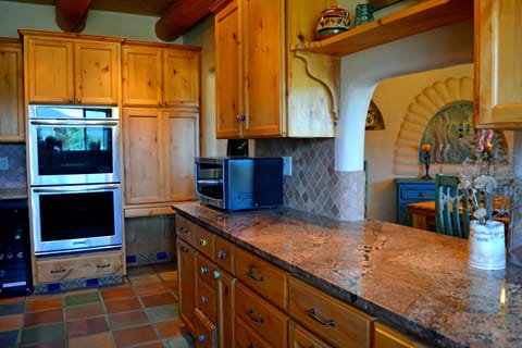 Wine/beverage cooler to left of double built in oven + pass through window between kitchen & dining for ease of serving & clean up