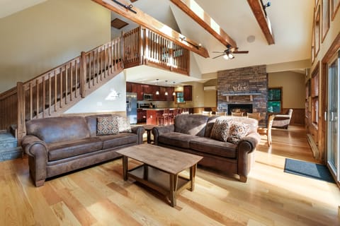 Picture of great room taken in front of fireplace, showing two couches, coffee table, and the kitchen (in the background).