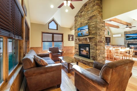 An angled photo of the fireplace of the great room behind the dining table, with seating and TV.