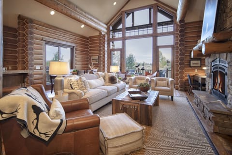 Unwind in this stunning log cabin living room where rustic charm meets modern comfort. Sink into plush leather seating by your crackling stone fireplace while floor-to-ceiling windows frame breathtaking mountain views.