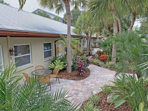 cexterior with patio seating area and lush tropical landscaping
