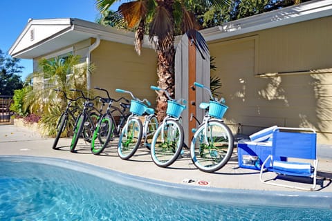 Community bicycles parked poolside with building exterior and tropical surroundings