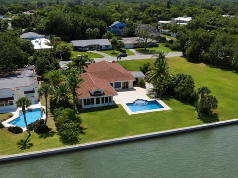 Aerial view of waterfront home showcasing the pool. There is no longer a dock or fence along the sea wall.
