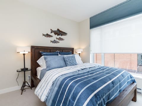 The restful main bedroom offers a peaceful sanctuary featuring a comfortable bed and large windows filtering in exceptional natural light.