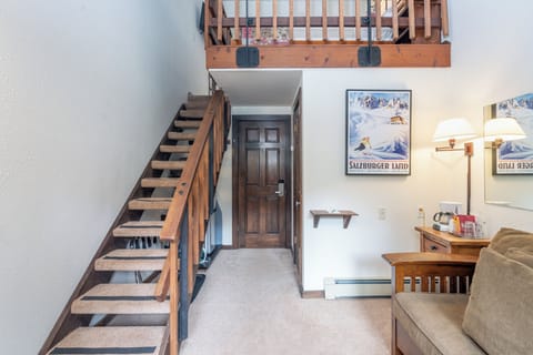 Step into your cozy loft retreat with soaring ceilings and alpine charm. The open layout invites relaxation, with stairs leading to your private sleeping space above.