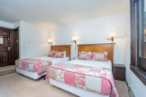 Drift off in your cozy bedroom, where two plush beds await with charming quilted bedding, warm reading lights, and a tranquil ambiance perfect for restful nights.