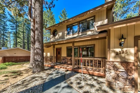Charming mountain cabin with stone details and welcoming front porch nestled among towering pine trees.