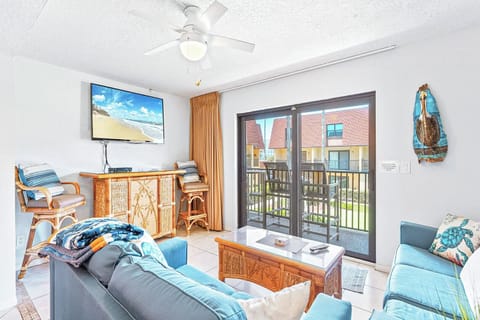Bright and airy living room with a cozy sofa, flat-screen TV, and patio access.