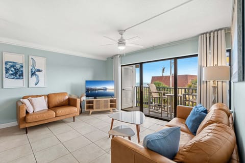 Bright and airy living room with a large TV and direct balcony access.