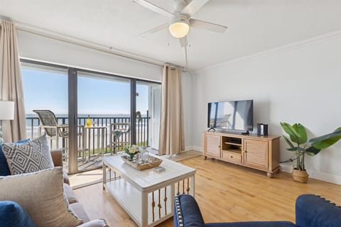 Bright and airy living room with comfortable seating and sliding glass doors that lead to oceanfront balcony