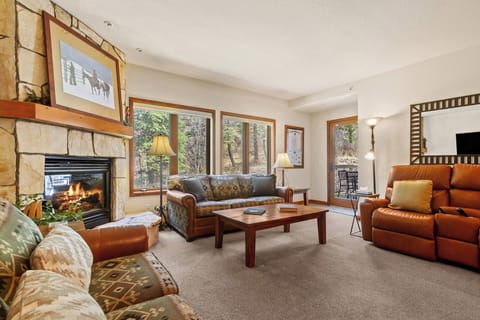 Unwind in your inviting living room with a fireplace, plush seating, and large windows framing tranquil nature views—your perfect mountain retreat awaits.