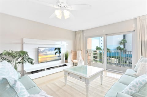 Bright and spacious living room with a 60” LCD TV, leading to a massive private balcony with breathtaking ocean views.