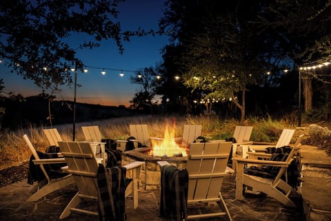 Gather around the crackling fire pit as twilight settles, with cozy Adirondack chairs and twinkling string lights creating your perfect evening retreat.