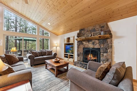 Cozy up by your crackling stone fireplace while watching forest views unfold through floor-to-ceiling windows in this rustic-modern retreat.