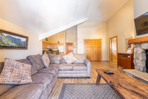 Sink into plush sectional seating by your cozy stone fireplace, where warm wood accents and mountain views create the perfect retreat.