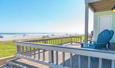 Your private deck overlooks endless sandy shores where ocean waves meet blue sky, perfect for morning coffee or sunset relaxation.