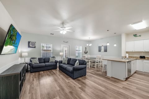 Relax in your spacious open-plan living area with plush seating, modern kitchen, and coastal artwork creating the perfect vacation atmosphere.
