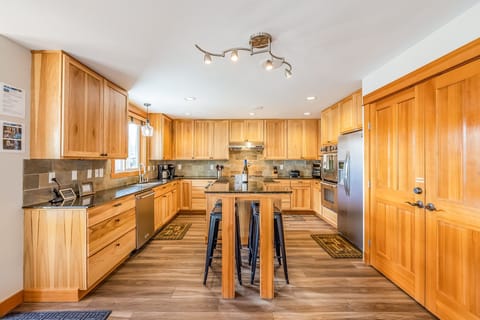 Chef's Kitchen w/ 6 Burner Gas Cook Top, Wall Ovens, and 4 Seating Center Counter Table