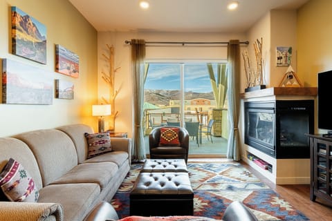Cozy living room with fireplace, mountain views, and balcony access.