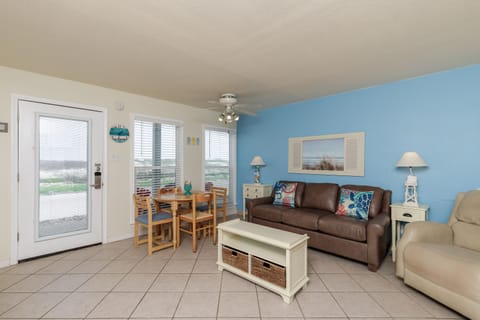 Your bright coastal living space features comfortable seating and dining areas with cheerful blue accent walls and beach-themed decor.